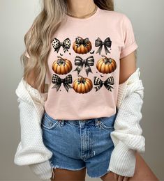 The Coquette Halloween Pumpkin Bow Shirt is a stylish and festive addition to your Halloween wardrobe. Featuring a charming pumpkin design adorned with a bow, this trendy shirt is the perfect Halloween gift for any fashion-forward individual. Whether you prefer a cozy sweater or a retro-inspired shirt, this piece effortlessly combines comfort with seasonal flair. Embrace the spirit of Halloween with this delightful and eye-catching shirt that promises to bring a touch of fun to your celebrations Fall Cotton Top With Bow Detail, Baby Blue Shirt, Pumpkin Sweater, Coquette Halloween, Halloween Bows, Bow Shirt, Bow Shirts, Trendy Halloween, Trendy Shirts