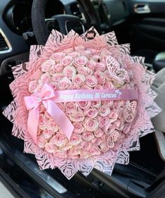 a bouquet of pink roses is sitting in the front seat of a car with a happy birthday message on it