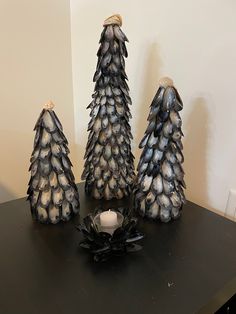 three small pine cones sitting on top of a black table next to a candle holder