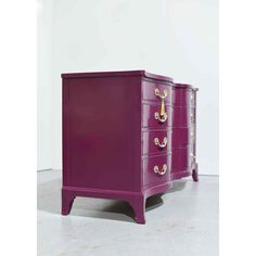 a purple dresser with gold handles and drawers on the bottom, in front of a white wall