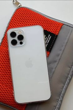 an iphone case sitting on top of a gray and orange pouch next to a cell phone