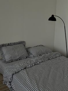 a bed with black and white striped bedspread next to a lamp on the wall