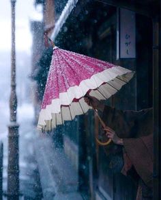 a woman is holding an umbrella in the rain while it snows on the street