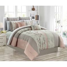 a bed with pink and grey comforters in a room