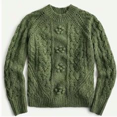 a green sweater with buttons on the front and back, sitting on a white surface