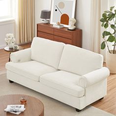 a living room with a white couch and wooden coffee table in front of a window