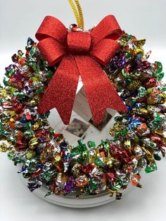 a christmas wreath ornament with a red bow hanging from it's side