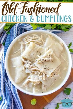 a bowl of chicken and dumpling soup on top of a wooden cutting board with green leaves