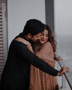 a man and woman hugging each other in front of the ocean