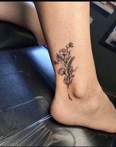 a woman's foot with a small flower tattoo on the side of her leg