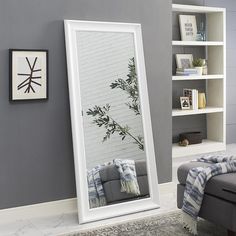 a living room with a large mirror on the wall next to a couch and bookcase