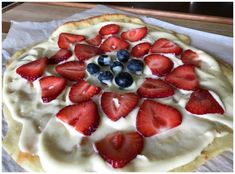 a pie with strawberries and blueberries on it sitting on top of a table