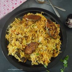 a black plate topped with food next to a fork and spoon on top of a table