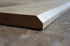 a piece of wood sitting on top of a wooden table next to a knife blade