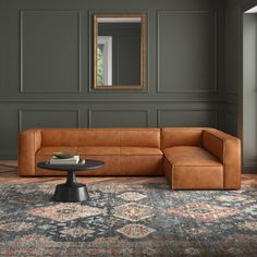 a brown leather couch sitting on top of a rug in a living room next to a mirror