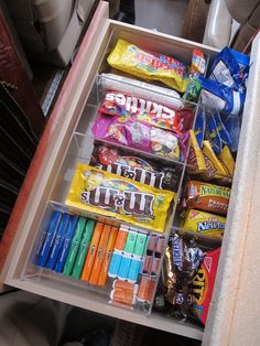 an open refrigerator filled with lots of food and candy bar wrappers on top of it