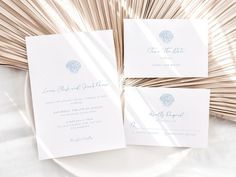 the wedding stationery is laid out on a white plate with palm fronds in the background