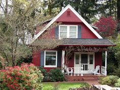 a red house with white trim and blue shutters in the front yard is surrounded by trees