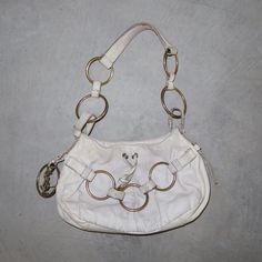 Gorgeous white leather YSL Saharienne bag from Tom Ford's era. Gold hardware. Good vintage condition but some dullness and marks to the leather, as pictured. Most notably the black marks from the rings rubbing on the leather. Nothing super bad.  MEASUREMENTS: Width: approx. 29cm Height: approx. 19cm Depth: approx. 5.5cm Handle Drop: approx. 26cm White Leather Bags With Brass Hardware, Vintage White Bags With Gold-tone Hardware, Vintage White Leather Shoulder Bag, White Vintage Leather Shoulder Bag, Women Accessories Bags, The Rings, Tom Ford, White Leather, Gold Hardware