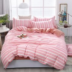 a bed with pink and white striped comforter in front of a window next to a pair of shoes