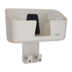 a white wall mounted device holder with two remote controls in the center and one on the other side