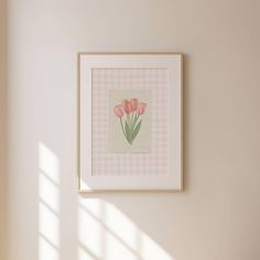 a pink and white checkered wall with some flowers in the frame hanging on the wall