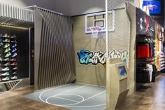 an indoor basketball court with graffiti on the walls and in between two lockers, there is a basketball hoop