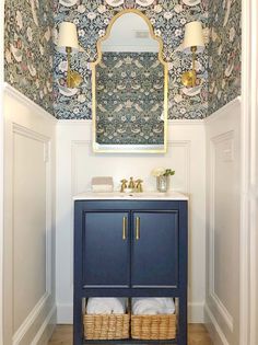 a blue cabinet with two baskets under it and a mirror on the wall above it