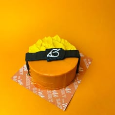 a yellow cake with a black ribbon around it on top of a piece of paper