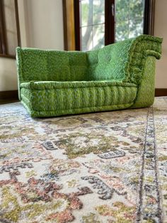 a green couch sitting on top of a rug