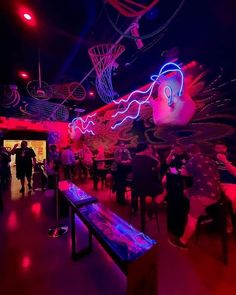 a group of people standing around in a room with neon lights on the walls and ceiling