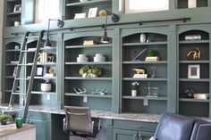 an office with green bookcases and leather chairs