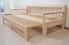 a wooden bed frame sitting on top of a hard wood floor next to a white wall