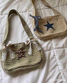 two crocheted purses sitting on top of a white bed next to each other