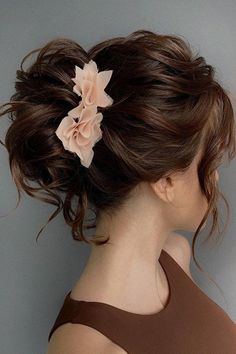 a woman with her hair in a messy updo and flower pinned to the side