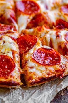 a pepperoni pizza sitting on top of a piece of wax paper