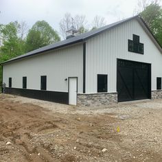 a large white barn with black doors and windows