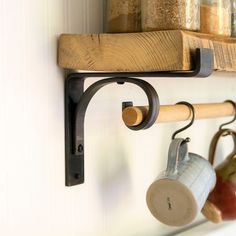 pots and pans are hanging on the wall next to a rack with wooden handles