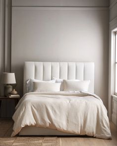 a white bed sitting in a bedroom next to a window