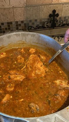 a large pan filled with food on top of a stove next to a person holding a knife