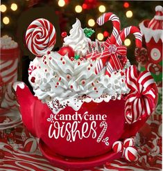 a red bowl filled with whipped cream and candy canes on top of a table