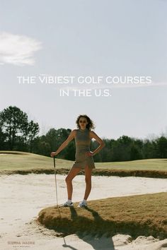 a woman standing in the sand holding a golf club