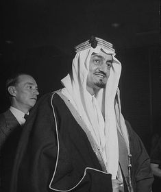 black and white photograph of a man dressed in an arab attire with two men standing behind him