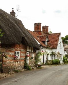 an old brick house with thatched roof and chimneys