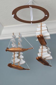 two wind chimes made out of wood and white sailboats hanging from the ceiling