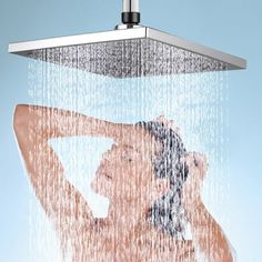 a shower head with water pouring from it and a woman's torso in the background