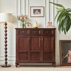 a wooden cabinet sitting next to a lamp on top of a table in a living room