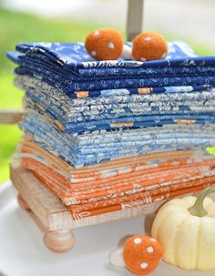 a stack of cloths sitting on top of a white plate next to a pumpkin