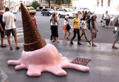 an ice cream cone shaped like an octopus is on the sidewalk as people walk by