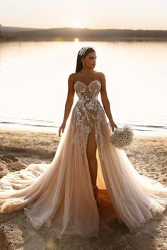 a woman is standing on the beach wearing a dress with high slits and flowers in her hair